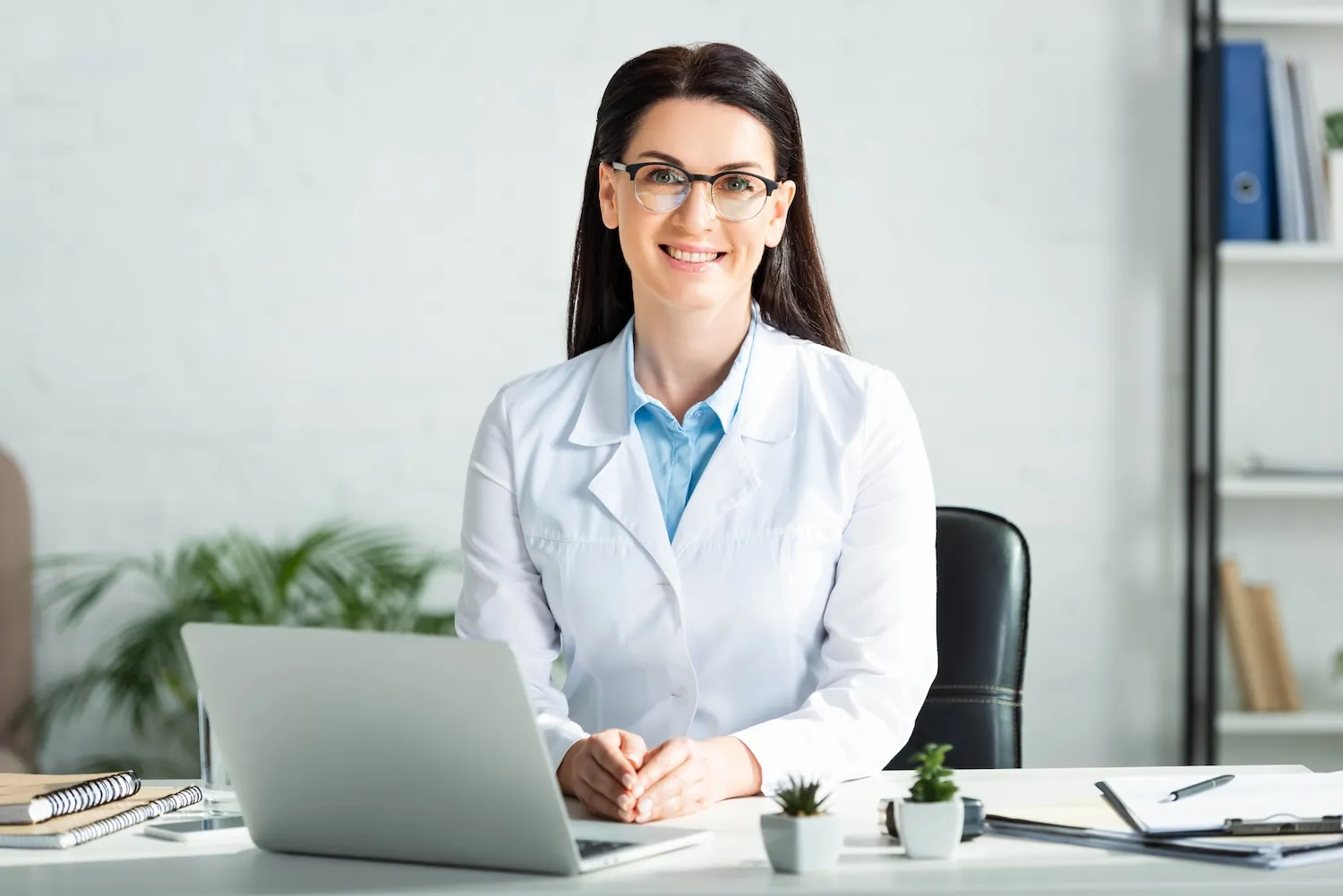 Doctor sitting in office, smiling while on the computer