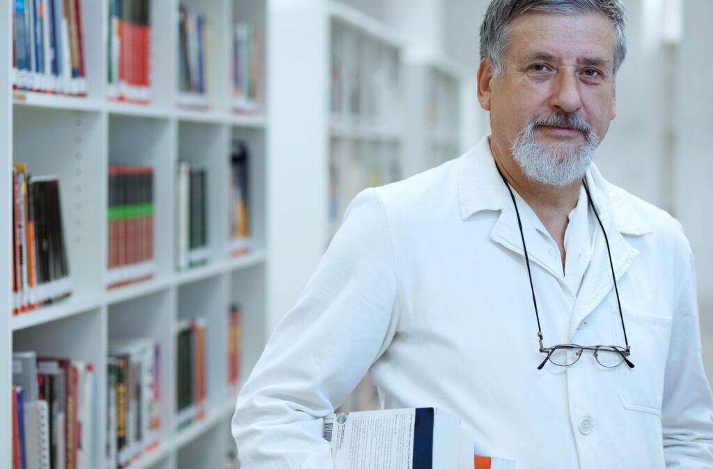 Middle aged doctor standing in front of bookshelf - VAT ENG Testing
